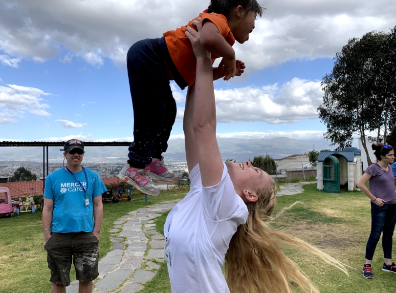 Volunteer lifts child overhead