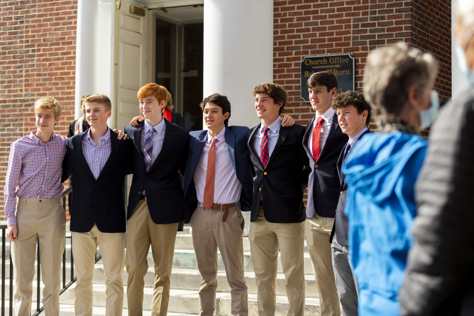 A group of teenage boys stand with their arms over one another's shoulders