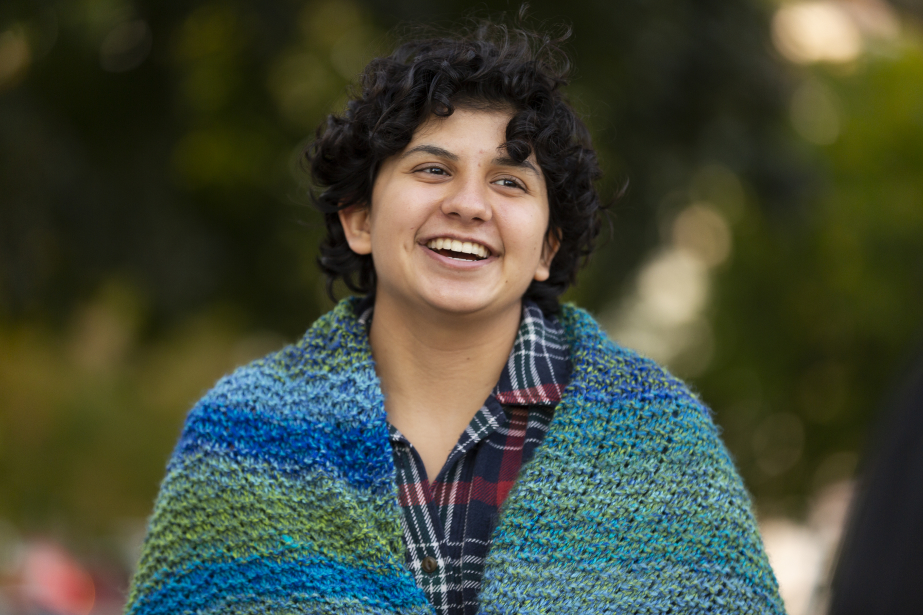 A woman wearing a colorful shawl smiles