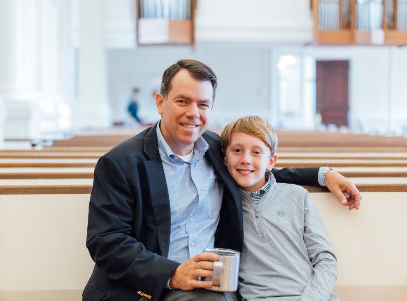 Man and his son sit together in pew