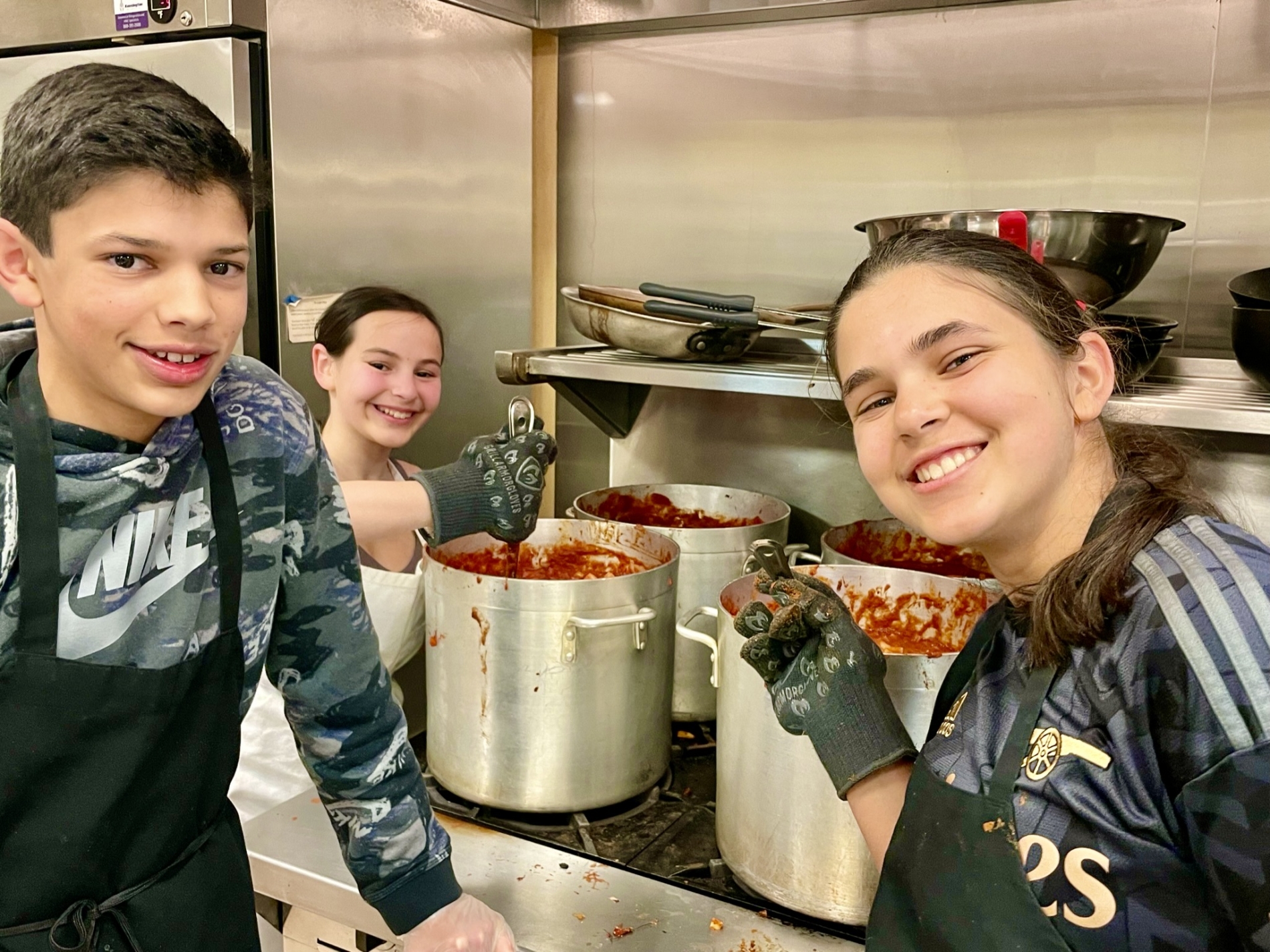 Three teenage volunteers cook together
