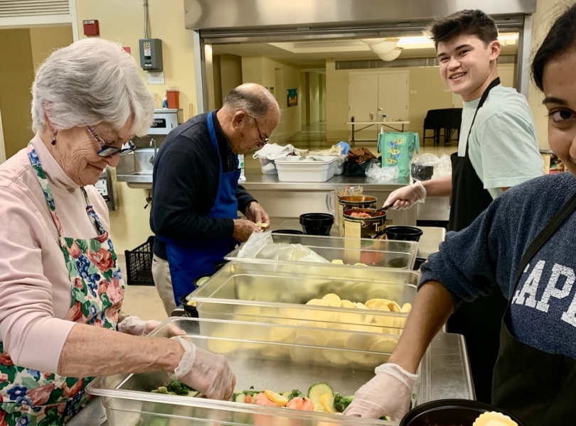 High school volunteers help prepare food at Village Table